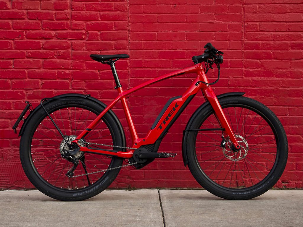 Stylish, red e-bike for commuting beside a brick wall.