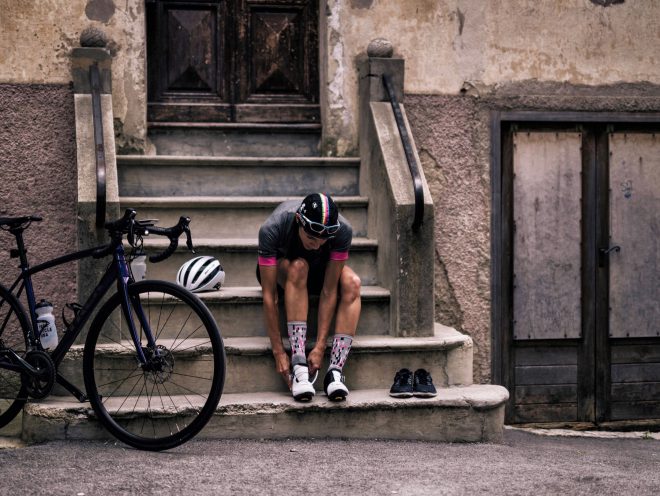 Cyclist putting on shoes while sitting on steps