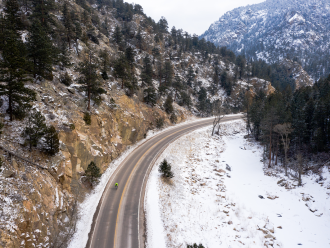 Cyclist riding up a mountain with snow on the side of the road