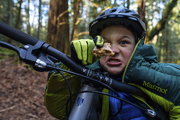 Kid looking over the handlebar with bread in hand, funny face