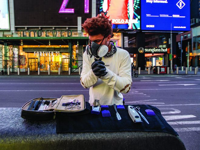 Julien Howard aka The Velo Barber wearing a mask and gloves prepares his stylist’s toolkit in an empty Times Square.