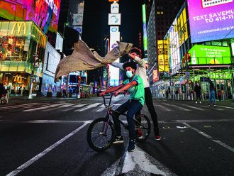 Julien Howard no centro da Times Square à noite, colocando uma capa em um cliente.