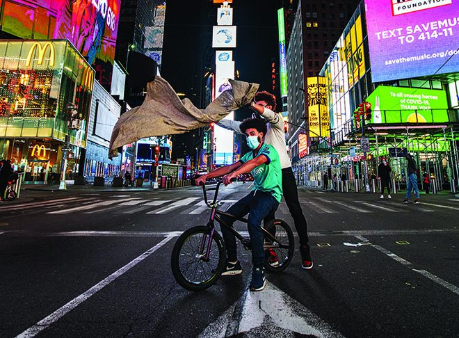 Julien Howard poniendo un delantal a un cliente por la noche en el centro de Times Square.