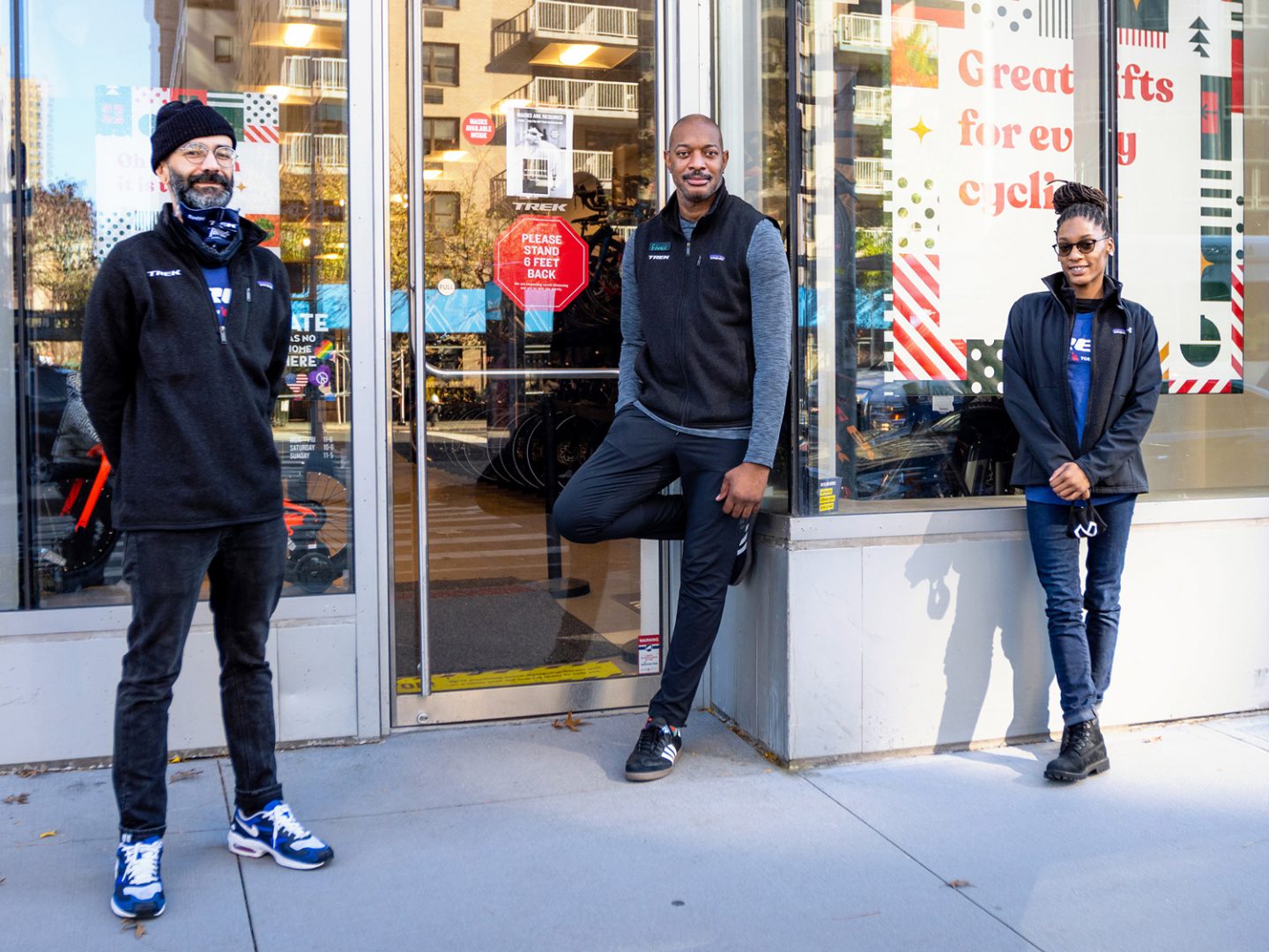 Three employees standing outside of a Trek store.