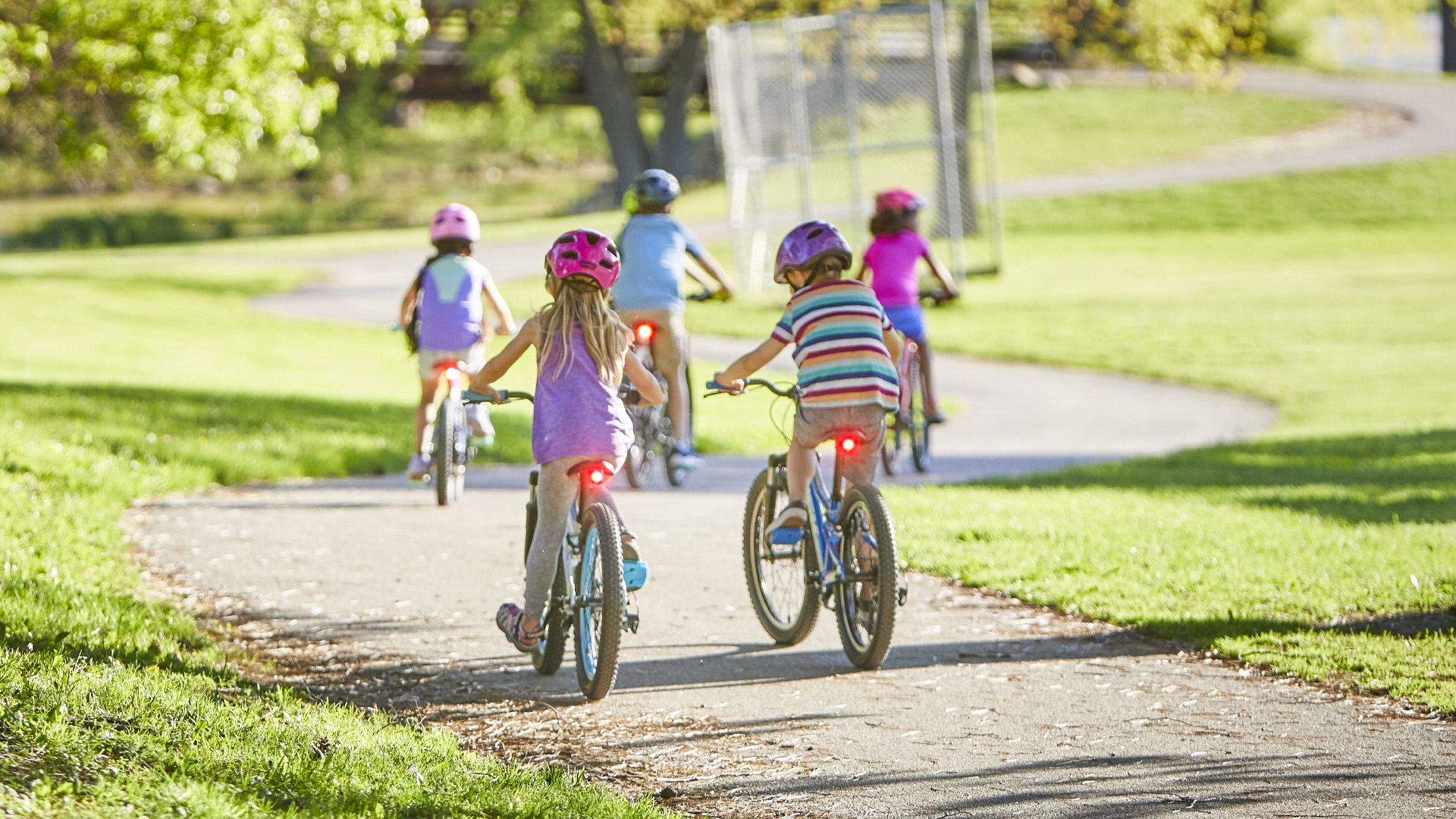 Dzieci z włączonymi lampkami tylnymi jadące po ścieżce rowerowej