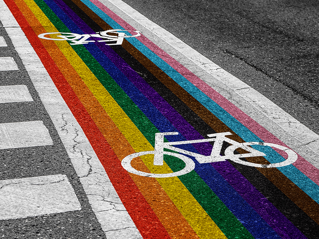 A bike path painted with the colors of the LGBTQIA+ flag.
