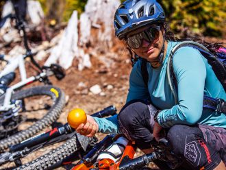 Christina Chappetta agachada na frente de sua bicicleta segurando uma laranja