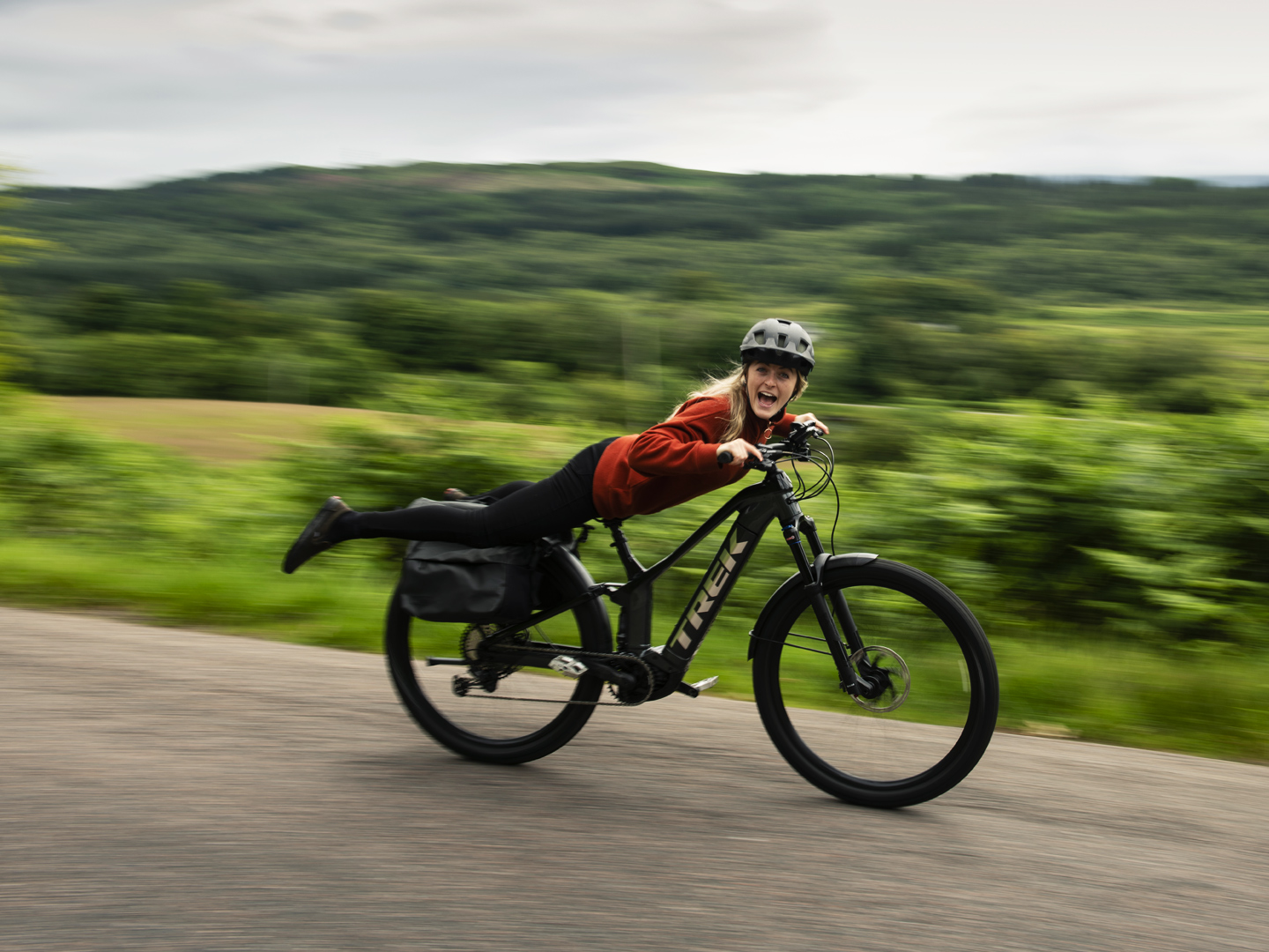 Lächelnde Radfahrerin macht einen Superman auf ihrem Bike