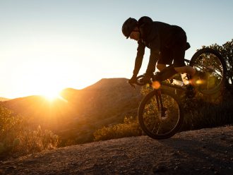 Man på cykel gör en stoppie på en grustäckt kulle