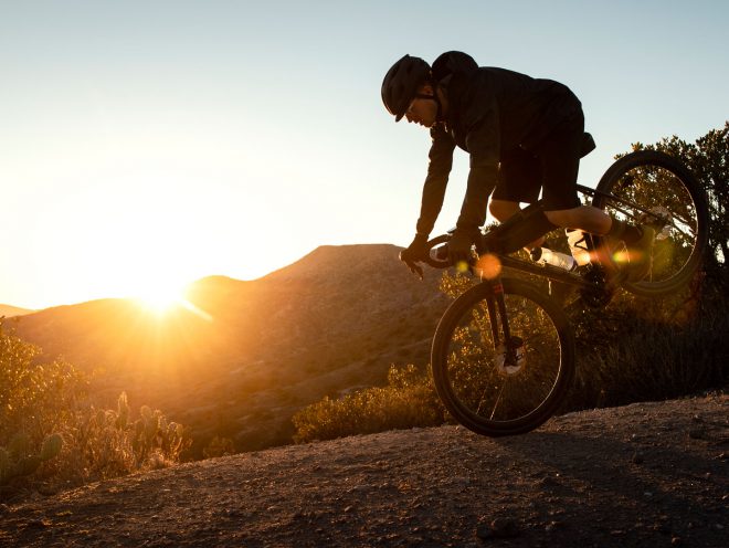 Man rides his bike and does a stoppie on a gravel hill