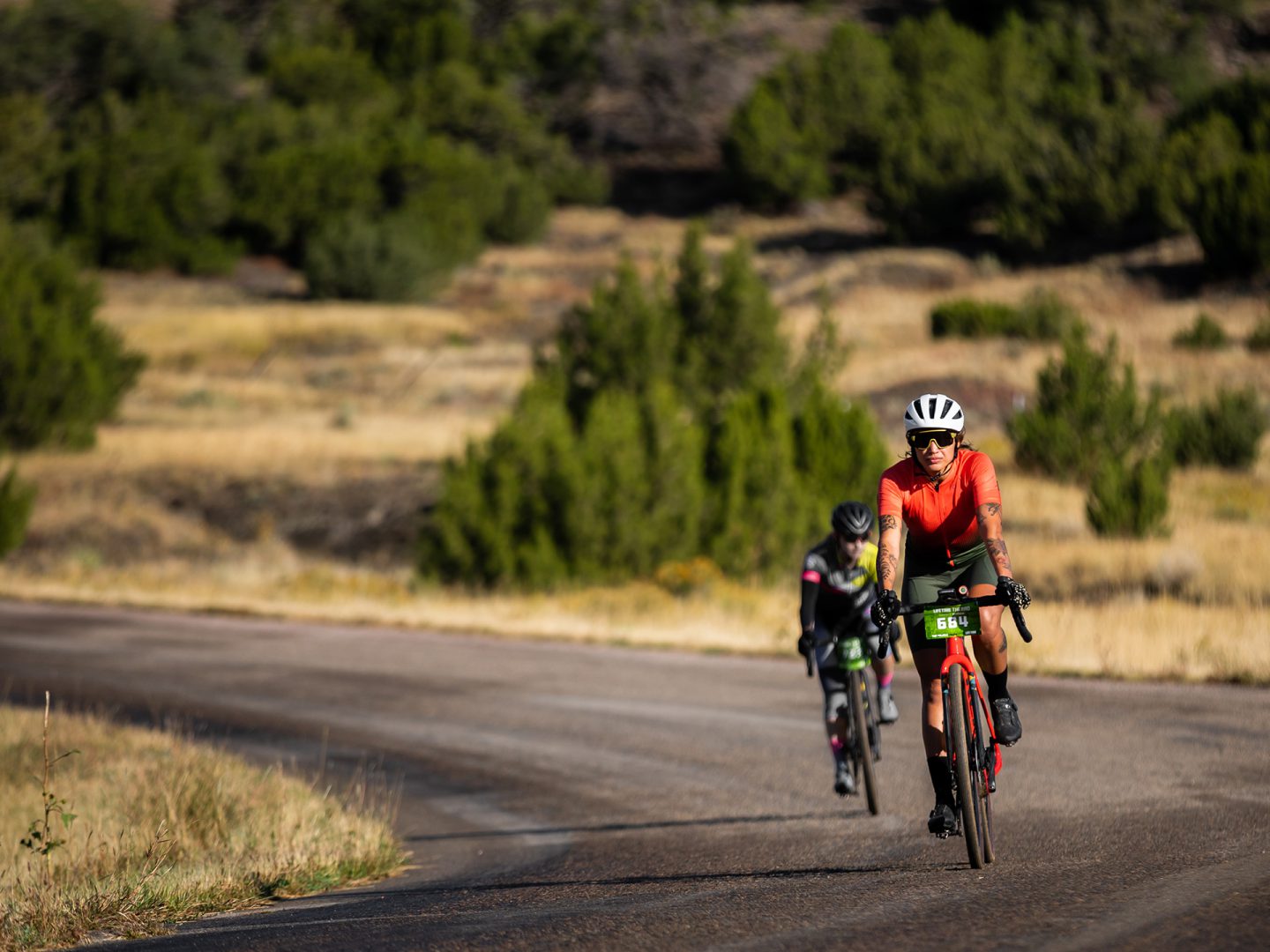 Dos ciclistas pedaleando hacia la cámara en una carretera de gravel