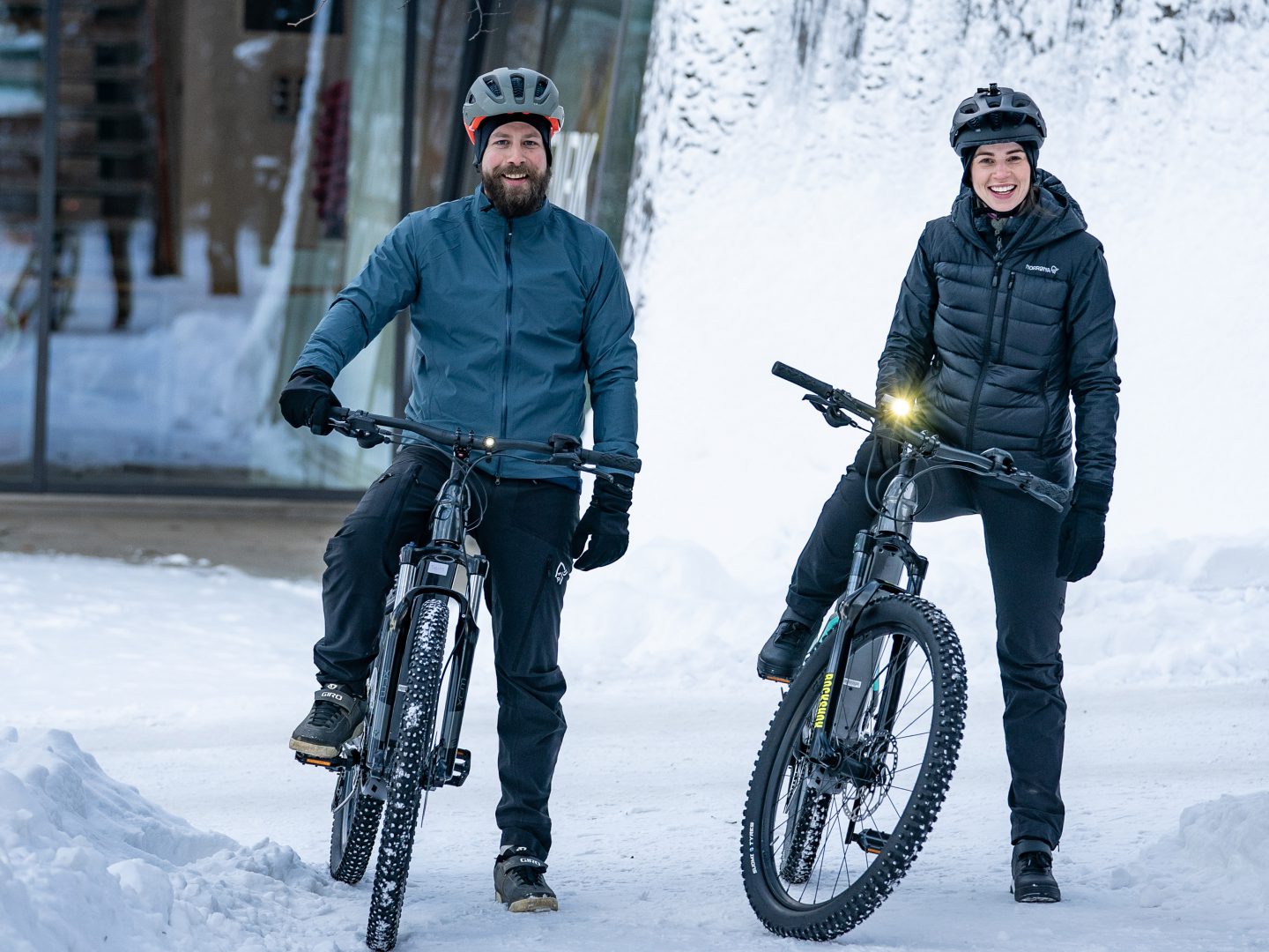 Två glada cyklister som cyklar under vinter