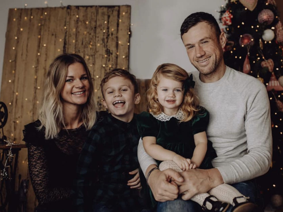 James Golding smiling with his wife and two children.