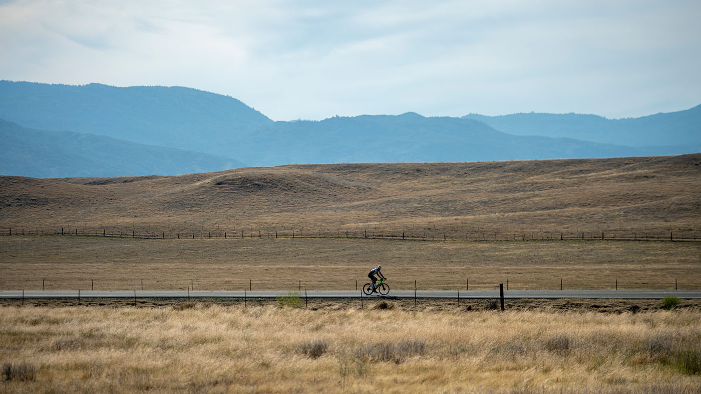 James rides his bike at a distance through Southern Colorado with mountains in the background.