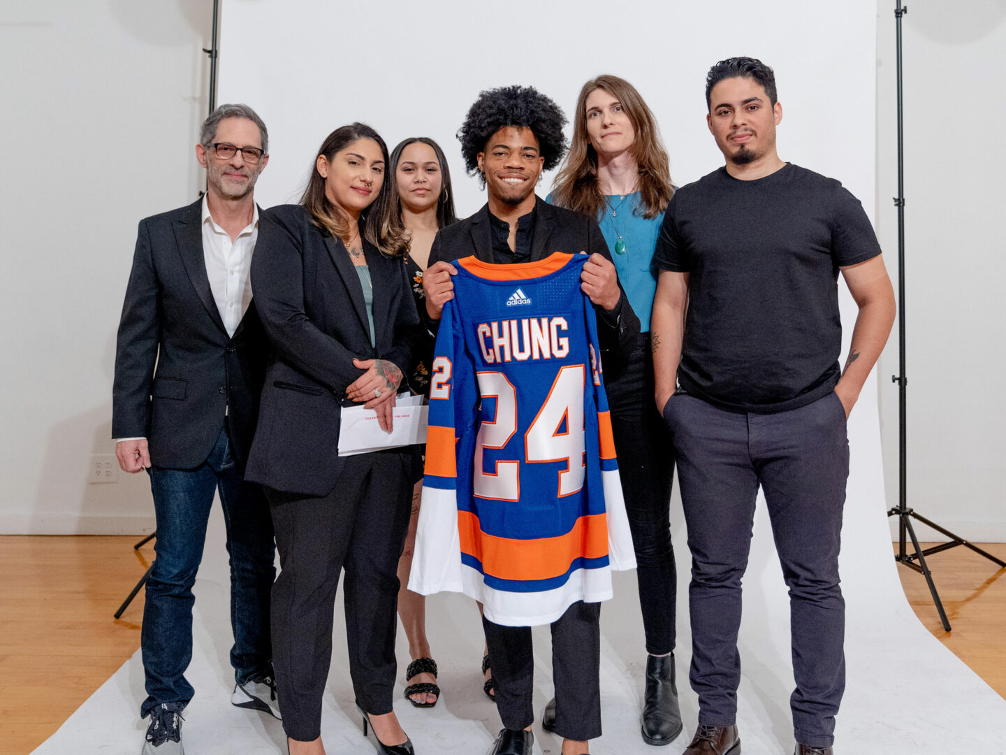 Hew poses with a group of mentors, holding a jersey with the name 