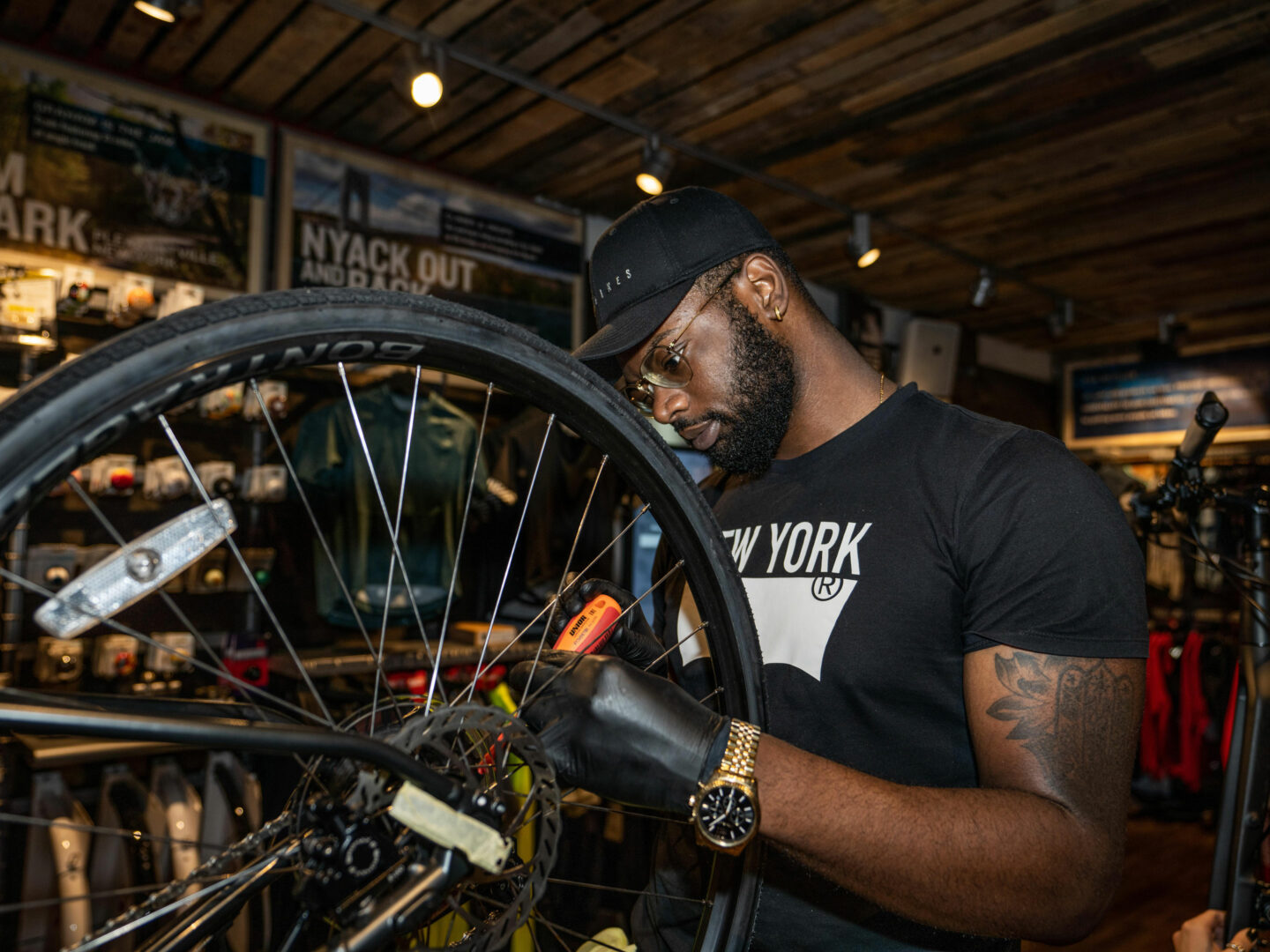 A young Black man works on a bicycle in a bike shop.