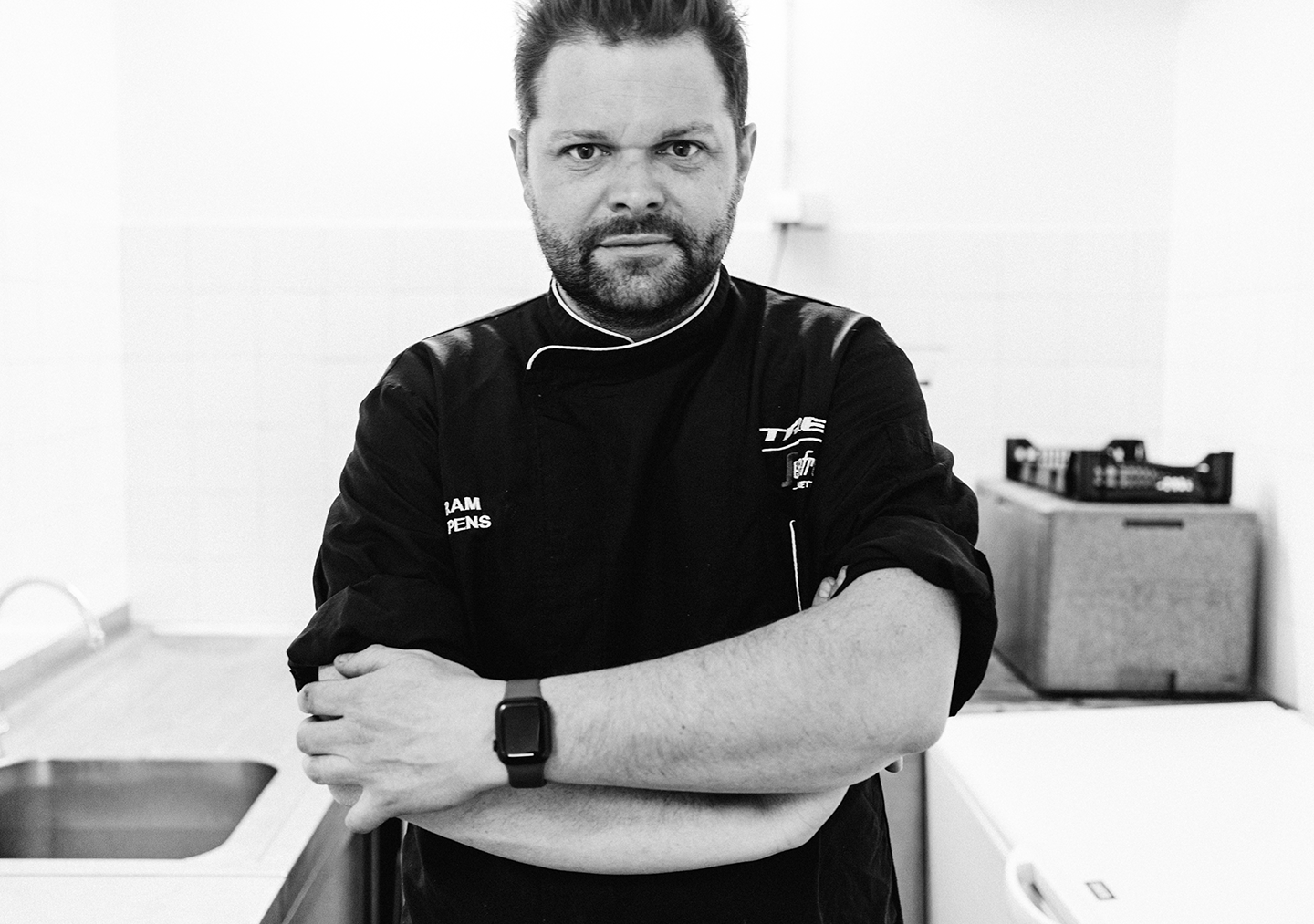 Chef Bram Lippens poses with his arms crossed in a kitchen.