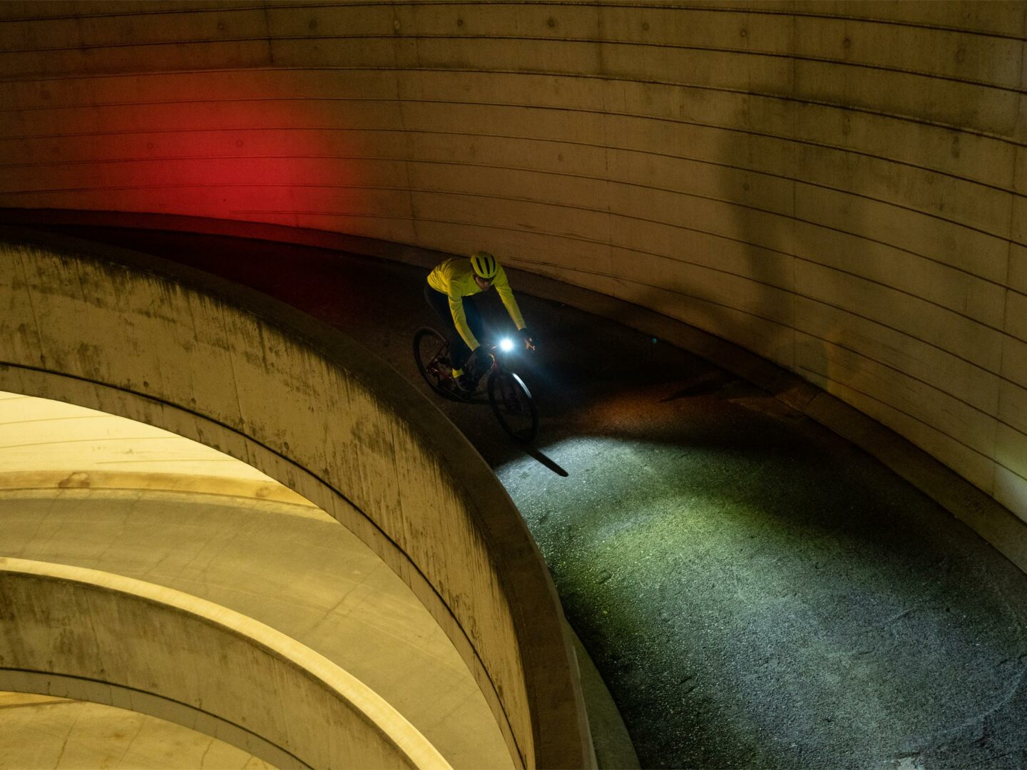Et bilde av en syklist ovenfra som sykler i mørket med lysene på