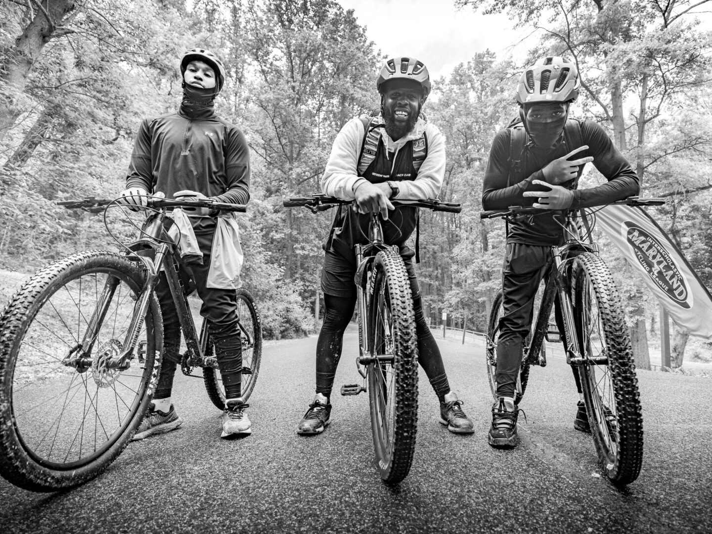 Coach Alex Clark and two riders from his NICA team standing over their mountain bikes.