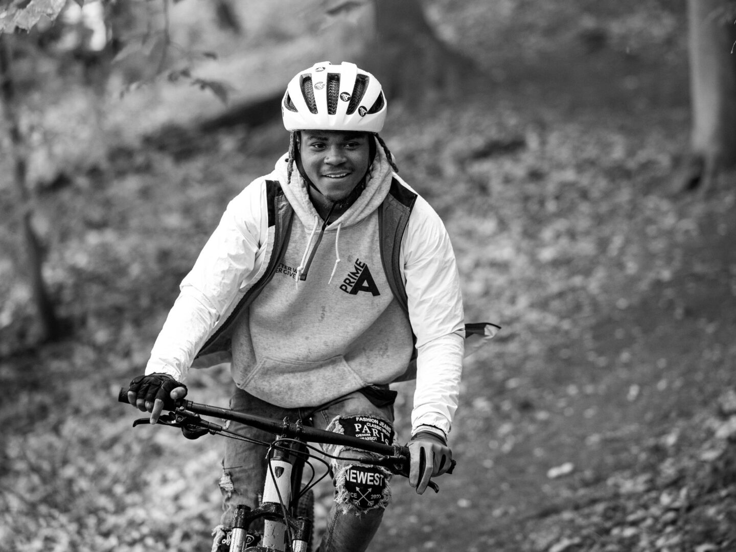 A smiling young cyclist riding his mountain bike down a dirt trail.