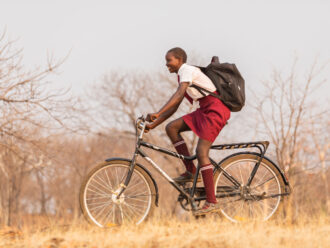 A girl riding her Buffalo Bicycle to school in a rural area of Kenya.